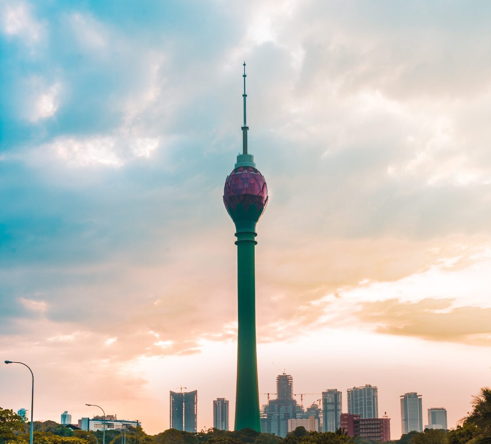 man in green jacket and blue denim jeans sitting on train rail during daytime